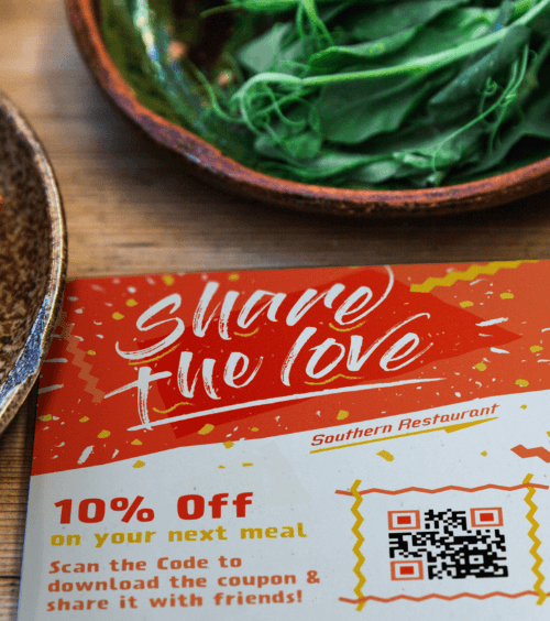 Un folleto promocional de un restaurante con un código QR que ofrece a los usuarios un cupón de descuento cuando es escaneado.